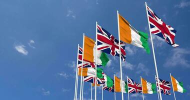 Ivory Coast and United Kingdom Flags Waving Together in the Sky, Seamless Loop in Wind, Space on Left Side for Design or Information, 3D Rendering video