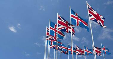 Iceland and United Kingdom Flags Waving Together in the Sky, Seamless Loop in Wind, Space on Left Side for Design or Information, 3D Rendering video