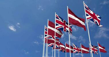 Latvia and United Kingdom Flags Waving Together in the Sky, Seamless Loop in Wind, Space on Left Side for Design or Information, 3D Rendering video