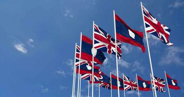 Laos und vereinigt Königreich Flaggen winken zusammen im das Himmel, nahtlos Schleife im Wind, Raum auf links Seite zum Design oder Information, 3d Rendern video