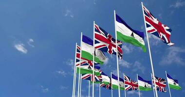 Lesotho and United Kingdom Flags Waving Together in the Sky, Seamless Loop in Wind, Space on Left Side for Design or Information, 3D Rendering video