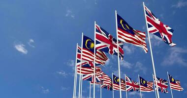 Malaysia and United Kingdom Flags Waving Together in the Sky, Seamless Loop in Wind, Space on Left Side for Design or Information, 3D Rendering video