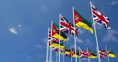 Mozambique y unido Reino banderas ondulación juntos en el cielo, sin costura lazo en viento, espacio en izquierda lado para diseño o información, 3d representación video
