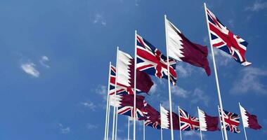 Qatar et uni Royaume drapeaux agitant ensemble dans le ciel, sans couture boucle dans vent, espace sur la gauche côté pour conception ou information, 3d le rendu video