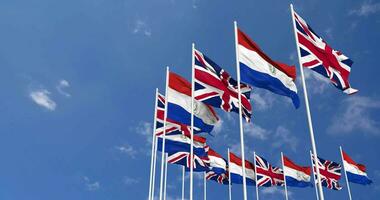 Paraguay and United Kingdom Flags Waving Together in the Sky, Seamless Loop in Wind, Space on Left Side for Design or Information, 3D Rendering video