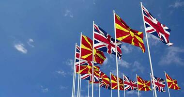 North Macedonia and United Kingdom Flags Waving Together in the Sky, Seamless Loop in Wind, Space on Left Side for Design or Information, 3D Rendering video