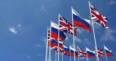 Russia and United Kingdom Flags Waving Together in the Sky, Seamless Loop in Wind, Space on Left Side for Design or Information, 3D Rendering video