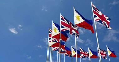 Filipinas y unido Reino banderas ondulación juntos en el cielo, sin costura lazo en viento, espacio en izquierda lado para diseño o información, 3d representación video