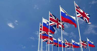 Slovenia and United Kingdom Flags Waving Together in the Sky, Seamless Loop in Wind, Space on Left Side for Design or Information, 3D Rendering video