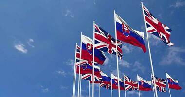 slovakia och förenad rike flaggor vinka tillsammans i de himmel, sömlös slinga i vind, Plats på vänster sida för design eller information, 3d tolkning video