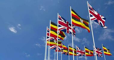 Uganda and United Kingdom Flags Waving Together in the Sky, Seamless Loop in Wind, Space on Left Side for Design or Information, 3D Rendering video