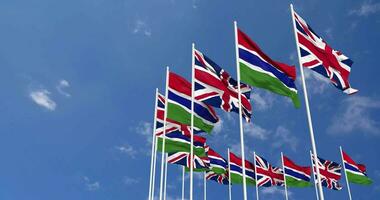 Gambia and United Kingdom Flags Waving Together in the Sky, Seamless Loop in Wind, Space on Left Side for Design or Information, 3D Rendering video