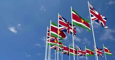 suriname et uni Royaume drapeaux agitant ensemble dans le ciel, sans couture boucle dans vent, espace sur la gauche côté pour conception ou information, 3d le rendu video