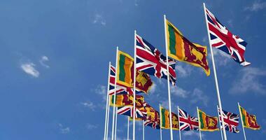 sri lanka et uni Royaume drapeaux agitant ensemble dans le ciel, sans couture boucle dans vent, espace sur la gauche côté pour conception ou information, 3d le rendu video