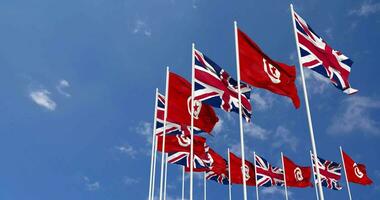 Tunisia and United Kingdom Flags Waving Together in the Sky, Seamless Loop in Wind, Space on Left Side for Design or Information, 3D Rendering video