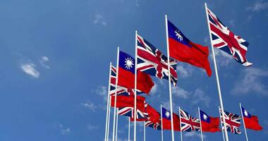 Taiwan e Unidos reino bandeiras acenando juntos dentro a céu, desatado ciclo dentro vento, espaço em esquerda lado para Projeto ou Informação, 3d Renderização video