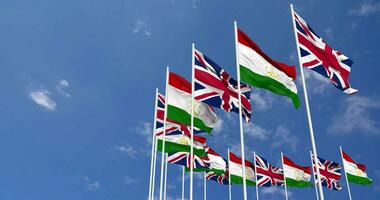 Tajikistan and United Kingdom Flags Waving Together in the Sky, Seamless Loop in Wind, Space on Left Side for Design or Information, 3D Rendering video