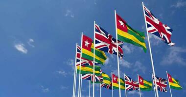 Togo and United Kingdom Flags Waving Together in the Sky, Seamless Loop in Wind, Space on Left Side for Design or Information, 3D Rendering video