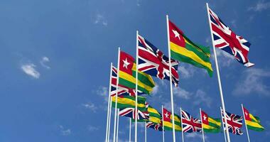 Togo and United Kingdom Flags Waving Together in the Sky, Seamless Loop in Wind, Space on Left Side for Design or Information, 3D Rendering video