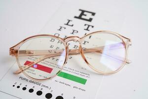 Glasses on eye exam chart to test eyesight accuracy of reading. photo