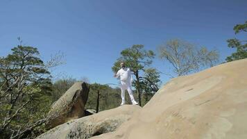 Man in White Attire on Rocks. Man in white clothing standing on large rocks. video