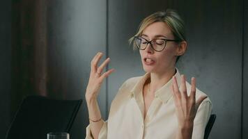 professionnel femme faire des gestes pendant discours, engagé femme d'affaires avec des lunettes faire des gestes avec sa mains tandis que Parlant dans un Bureau environnement. video