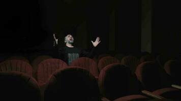 jubiloso público membro dentro esvaziar teatro, homem com barba, alegremente levantando braços dentro a esvaziar sentado em vermelho teatro, expressivo emoção video