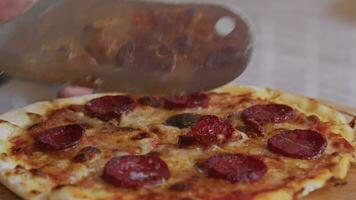 uma homem dentro a avental puxa pizza Fora do uma a lenha forno. uma cozinhar puxa Fora uma cozinhou pizza. queimando Comida dentro uma a lenha forno. ampla faca cortes pizza com queijo. cozinhando Comida sobre a aberto fogo. natural video