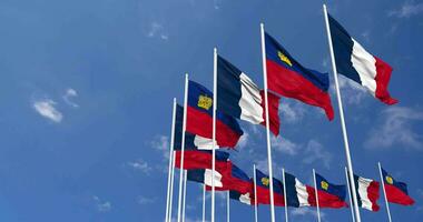 Liechtenstein et France drapeaux agitant ensemble dans le ciel, sans couture boucle dans vent, espace sur la gauche côté pour conception ou information, 3d le rendu video