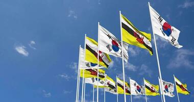brunei e Sud Corea bandiere agitando insieme nel il cielo, senza soluzione di continuità ciclo continuo nel vento, spazio su sinistra lato per design o informazione, 3d interpretazione video