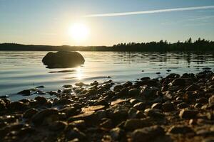 Lake in Sweden, smalland at sunset with rock in foreground of water with forest photo