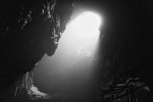 Rock cave with hole through which light shines. Underworlds in Sweden. Mystical photo