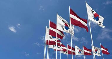 Lettland und Süd Korea Flaggen winken zusammen im das Himmel, nahtlos Schleife im Wind, Raum auf links Seite zum Design oder Information, 3d Rendern video
