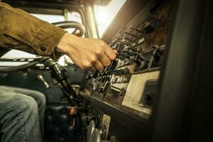 Driver Switching Dashboard Buttons Inside His Classic Semi Truck photo