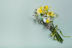 Easter spring bouquet with daffodils and willow on green background with copy space. Easter greeting card photo