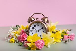 alarma reloj con primavera flores primavera tiempo, luz ahorros concepto, primavera adelante foto