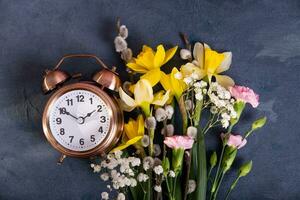 alarma reloj con primavera flores primavera tiempo, luz ahorros concepto, primavera adelante foto