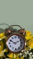 Alarm clock with spring flowers on color background. Spring time, daylight savings concept, spring forward photo