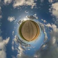 green tiny planet in evening blue sky with beautiful clouds. Transformation of spherical panorama 360 degrees. Spherical abstract aerial view. Curvature of space. photo