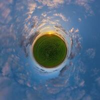 green tiny planet in evening blue sky with beautiful clouds. Transformation of spherical panorama 360 degrees. Spherical abstract aerial view. Curvature of space. photo