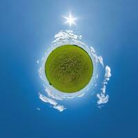 green tiny planet in evening blue sky with beautiful clouds. Transformation of spherical panorama 360 degrees. Spherical abstract aerial view. Curvature of space. photo