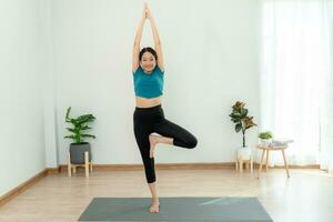 Slim woman practicing yoga on room of her condo or home. Asian woman doing exercises in morning. balance, meditation, relaxation, calm, good health, happy, relax, healthy lifestyle, diet, slim photo