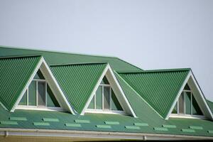 The house with plastic windows and a green roof of corrugated sheet. Green roof of corrugated metal profile and plastic windows. photo