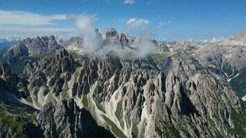 antenne visie van cadini di misurina bergen met tre cime di lavaredo bergen in de achtergrond gedurende een zonnig dag met sommige wolken. dolomieten, Italië. dramatisch en filmische landschap. video