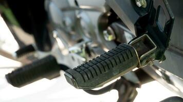 Close up of motorcycle footrest pedals. under view of motercycle stop with stand. Bright of sunlight for background. photo