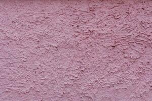 Rough surface of a fence wall or house wall.  Wall pink color paint. photo