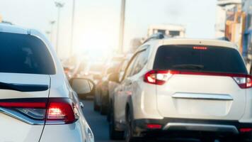 Rear side of white car with turn on brake light on the road. Traffic congestion during rush hour. City with light poles lit up on the road. Many cars lined up in a line. photo