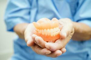 Doctor holding teeth denture in hand for dentist studying about dentistry. photo