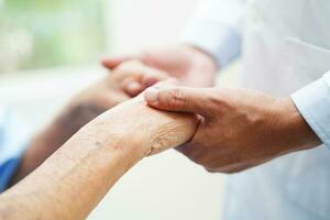 Doctor holding hands Asian elderly woman patient, help and care in hospital. photo