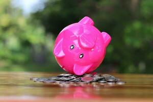 Piggy bank upside down on the pile of coins isolated on the table. photo